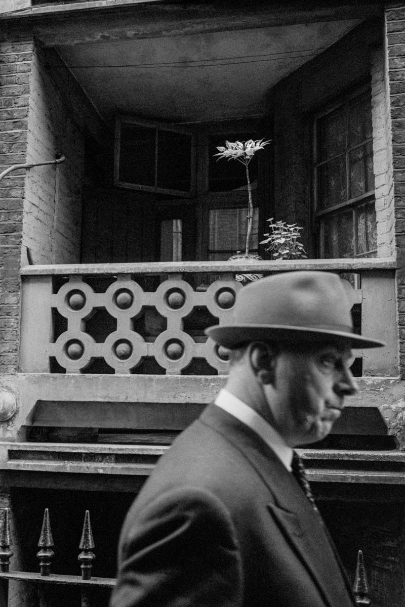 GB. ENGLAND. London. Soho. Man walking past flower. Taken on a Contax 2 camera (first professional camera). 1958.