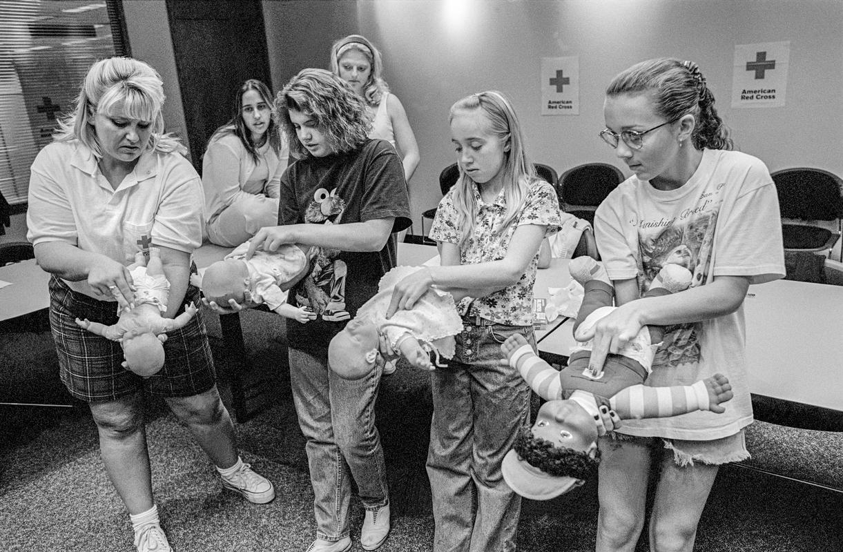 USA. ARIZONA. Phoenix. Red cross baby sitting classes. Red Cross workers run baby sitting classes in the Phoenix chapter. The students are aged from 11-15. They learn how to protect children from accidents and injury. They learn first aid for choking and bleeding, mouth to mouth and the Heimlich manoeuvre, and dealing with crying and changing diapers etc. At the end of the course they receive a certificate. Here we see learning the Heimlich manoeuvre. 1997.