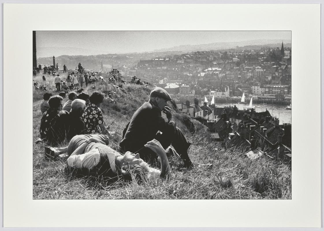 A sunny Sunday afternoon brings tourists and residents on to the hill overlooking Whitby harbour to relax and dream. England, Whitby.