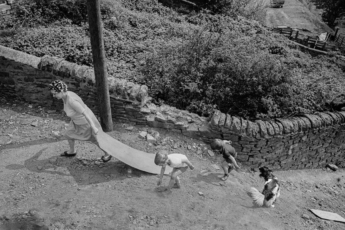 GB. WALES. Abertillery. Family climbing to the top of a slag heap with a piece of board to use it as a slide. 1977.