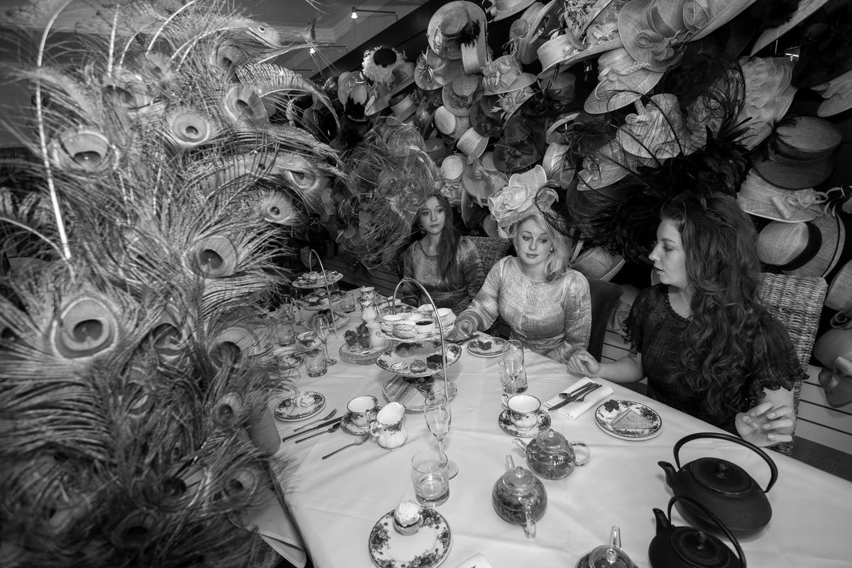 GB. WALES. Abergavenny. Alison Todd hat shop. Assistants at tea party. 2014.