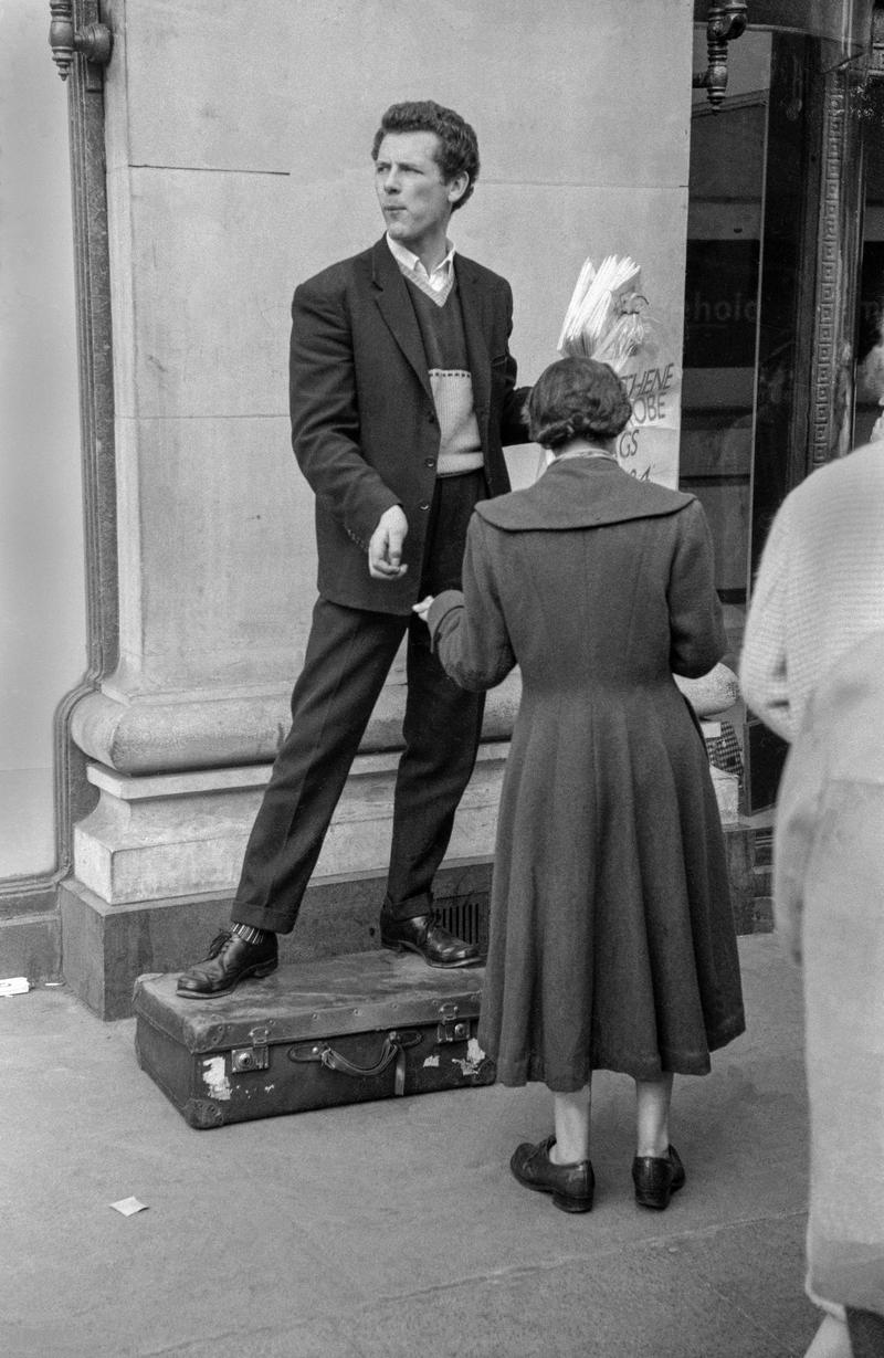 GB. ENGLAND. London. Street trader in Oxford Street. One of the first pictures ever taken by David Hurn, shot on a Kodak folding Retina camera (first camera). 1955.