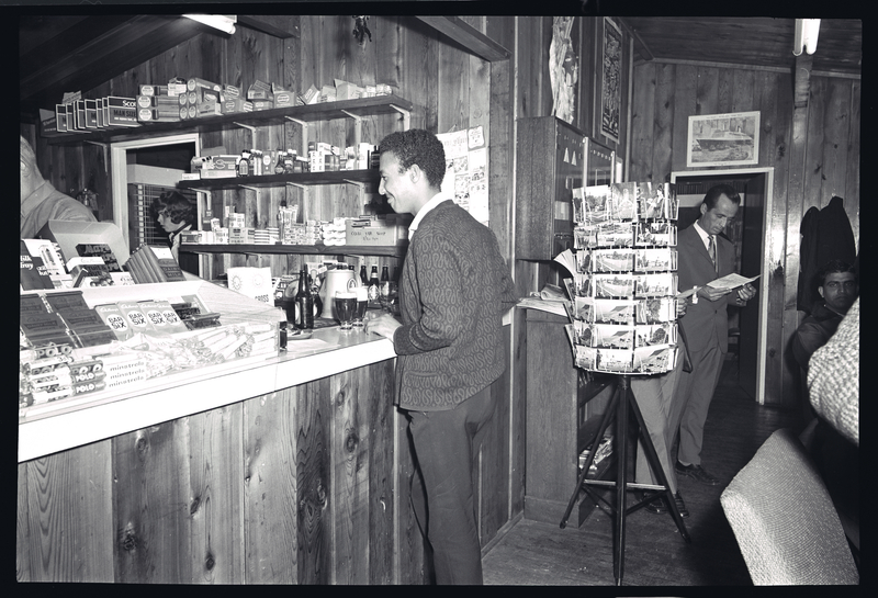 Man standing at a counter/bar, being served drinks