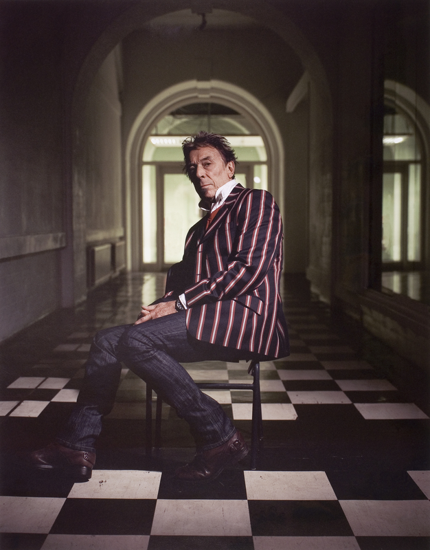 Portrait photograph of John Cale seated, at Goldsmiths, University of London.