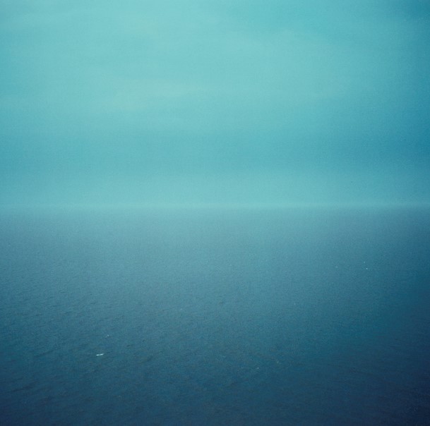A square photograph of a blue sky above a blue sea in misty weather