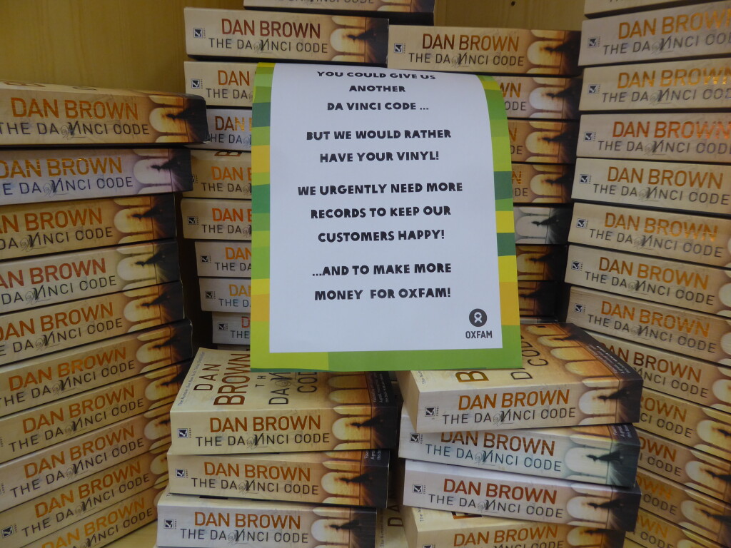 A stack of copies of Dan Brown's The Da Vinci Code with a sign from Oxfam asking for no more donations.