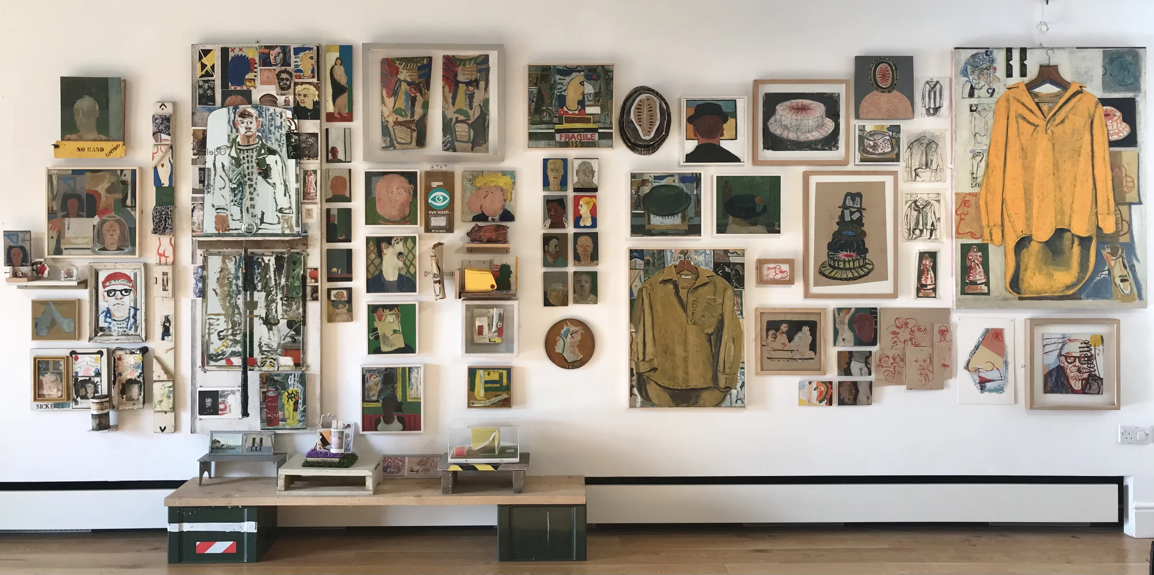 A variety of colourful paintings on a white wall.