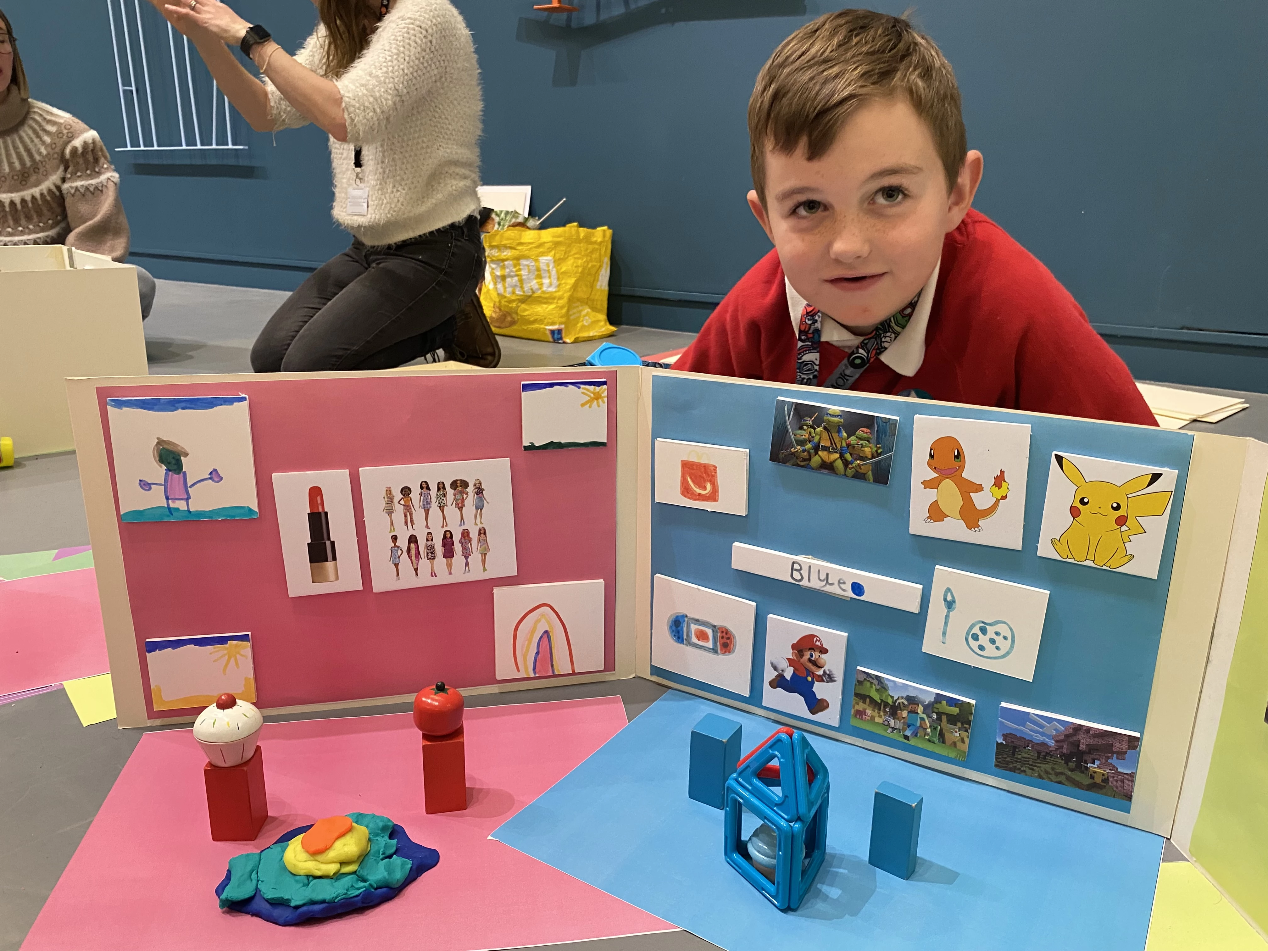 A boy sits behind his own drawings and pictures of artworks that inspire him.