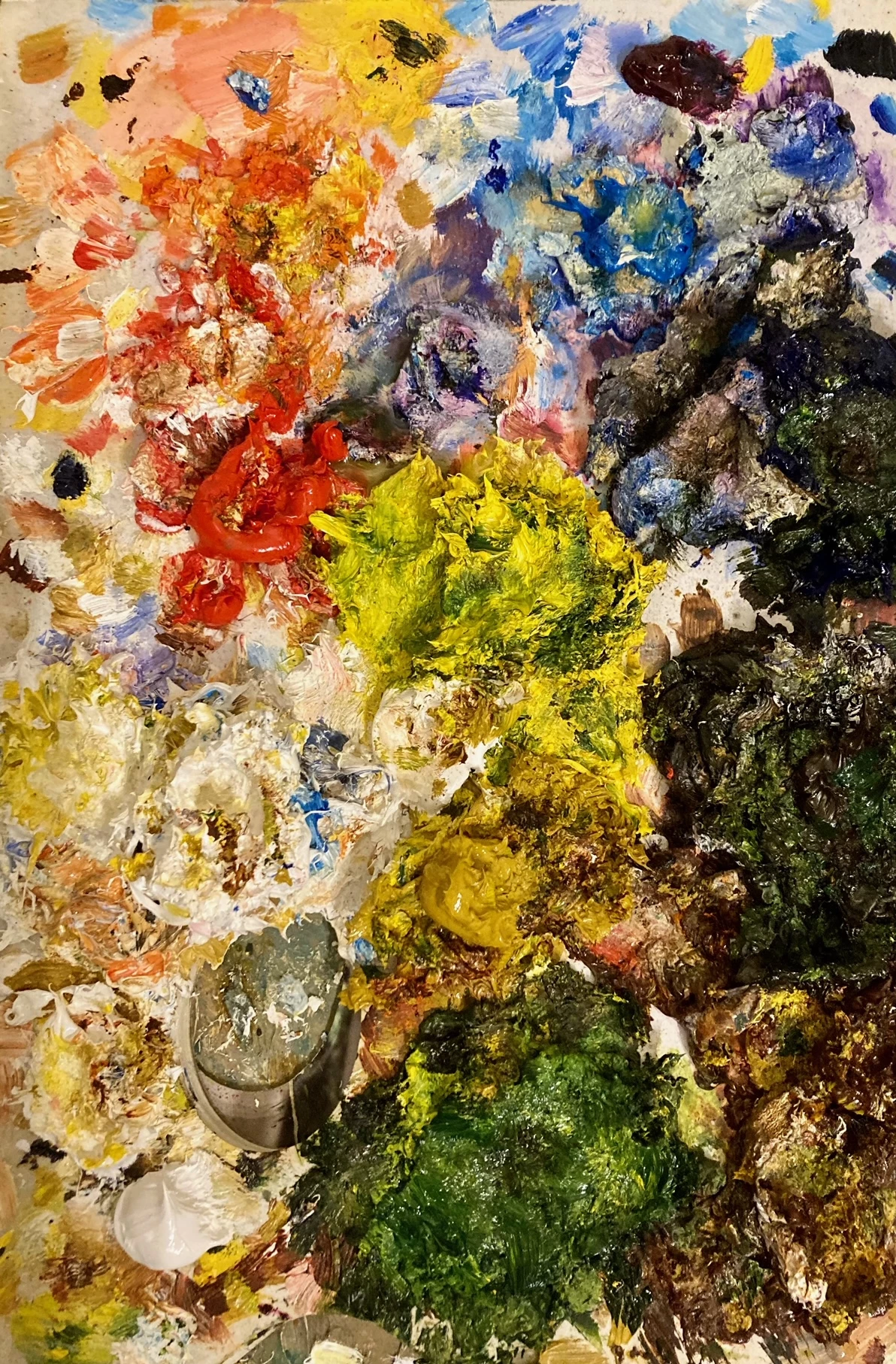 Photograph of oil paint palette - the palette is covered in thick paints of all colours.