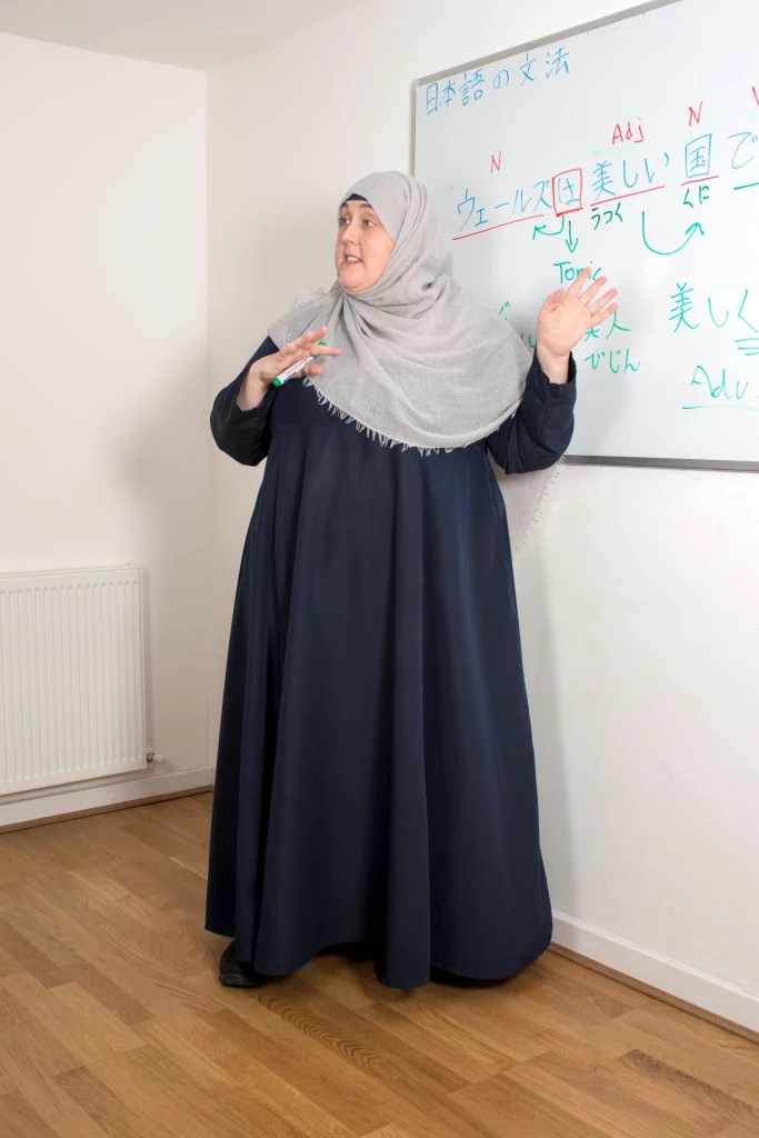 A teacher stands in front of a whiteboard covered in notes