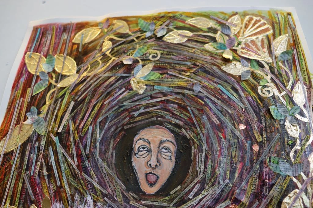 Detail photograph of a colourful mixed media collage of a woman's face, as if in a bird's nest, encased by branches with leaves.